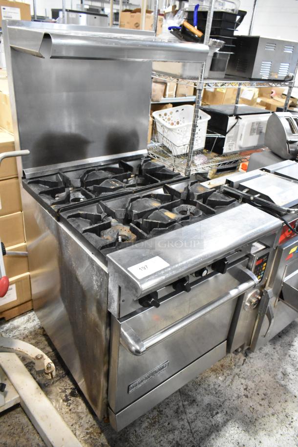 Commercial stainless steel stove with 10 burners and oven. Tag labeled "197." Used condition with visible wear.