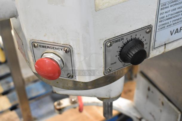 Close-up of industrial machine's emergency stop button and timer dial. Sturdy build, shows signs of use.