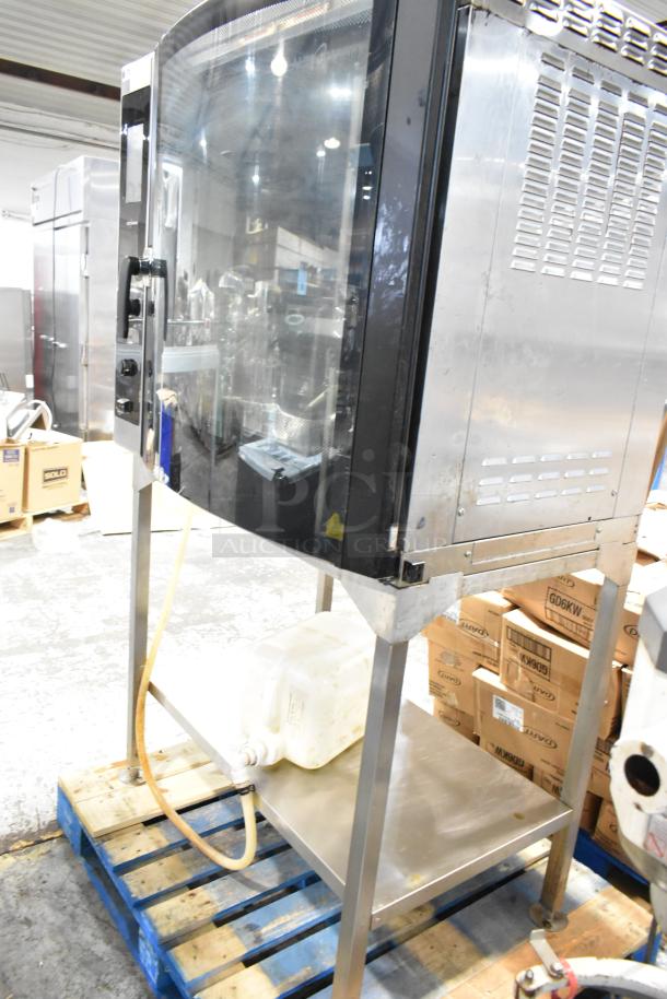 Industrial commercial oven on a stainless steel stand, with a large glass door and visible piping, used condition.