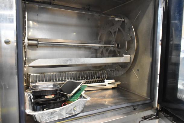 Industrial oven interior with rotating mechanism and racks. Includes metal tray with electronic components. Shows signs of use.