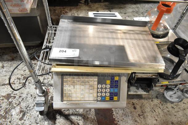 Digital commercial scale with keypad and stainless steel weighing platform. Auction tag "#204." Well-used condition.
