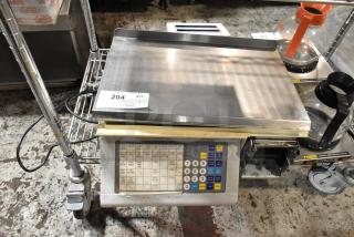 Digital commercial scale with keypad and stainless steel weighing platform. Auction tag "#204." Well-used condition.