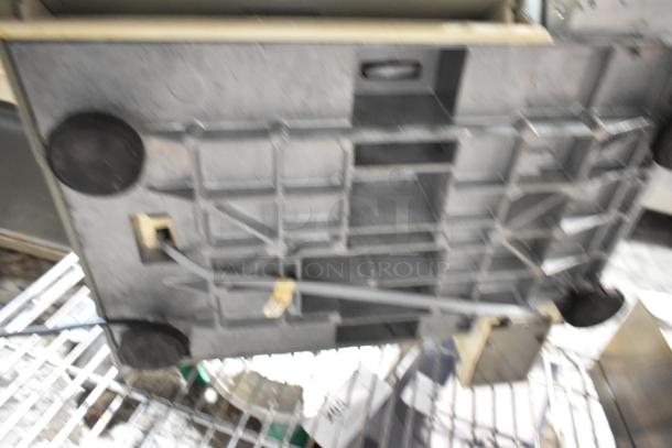 Underside view of a stainless steel kitchen appliance with power cable and black rubber feet. Signs of wear present.
