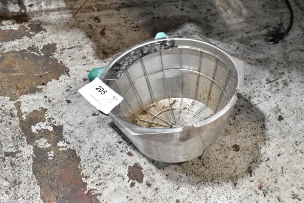 Metal strainer with green handles, visible wear and rust stains, auction tag numbered 205 attached, on a worn surface.