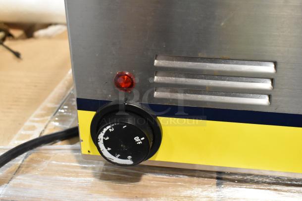 Close-up of a stainless steel appliance featuring a red indicator light, a rotary dial with numbered settings, and a yellow panel.