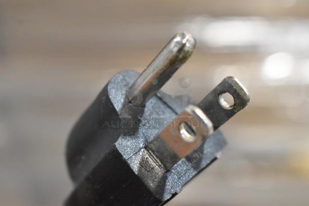 Close-up of a two-prong electrical plug with visible wear and markings indicating electrical specifications.