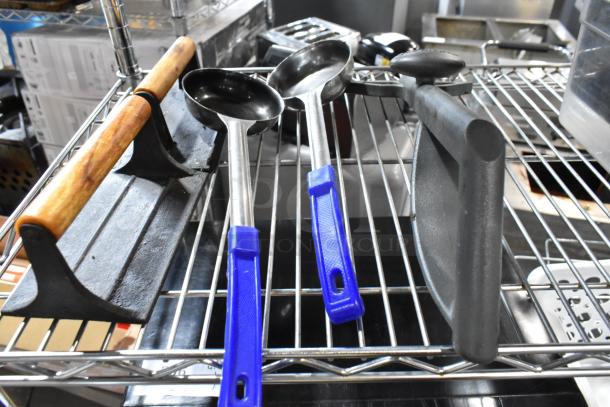 Metal utensils and cast iron bacon press on a wire rack, featuring wooden and blue handles, in used condition.