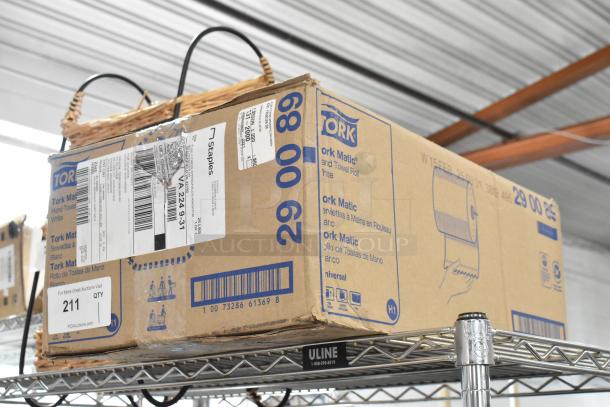 Box of Tork Matic hand towel rolls on a metal shelf, labeled with shipping tags and manufacturer details.