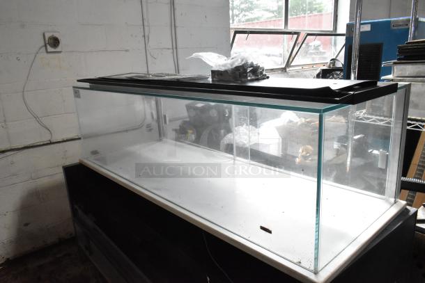 Large, rectangular glass aquarium with black lid, used condition, some dust visible. Plastic bag with parts on top.