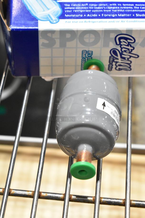 Gray Catch-All filter-drier with green caps, new in box. Ideal for refrigeration systems, protects against moisture and acids.
