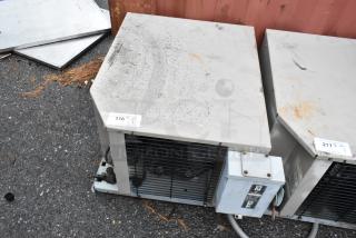 Commercial refrigeration unit with metal casing, visible wear and dirt. Tag indicates item number 216, auction quantity one.