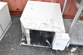 Commercial air conditioning unit by Eaton, visible wear and stains, model number and tags partially obscured.