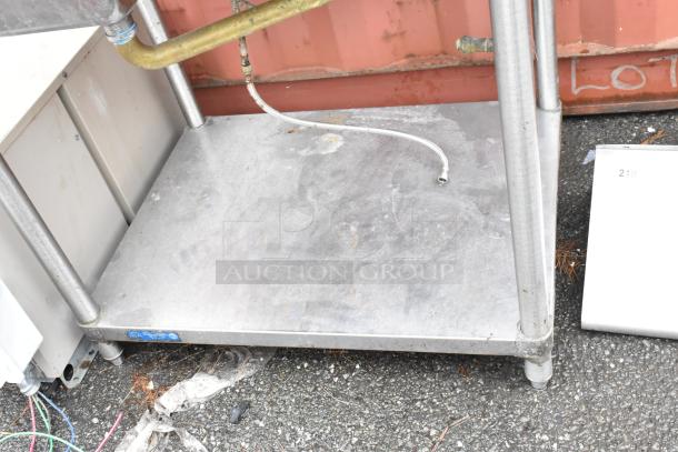 Stainless steel utility table with visible plumbing fixtures and slight wear, ideal for industrial use. No visible labels.