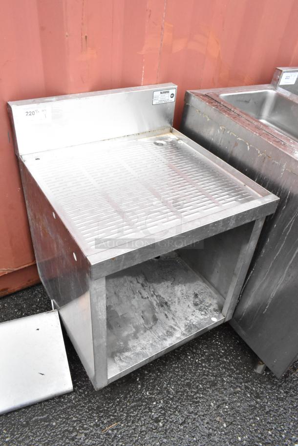 Stainless steel commercial drainboard table with backsplash; used condition, visible wear. Label indicates model and serial number.
