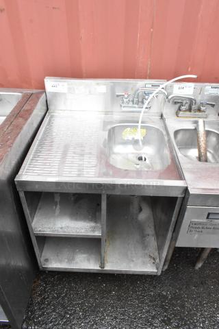 Stainless steel commercial sink with drainage surface, single basin, and faucet. Visible wear and rust. Auction tag "224".
