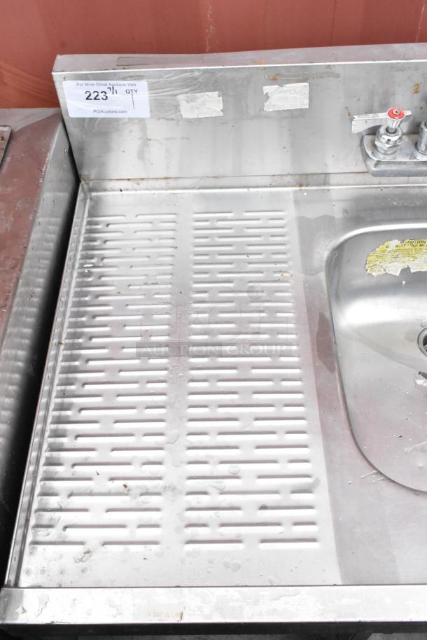 Stainless steel industrial sink with faucet, attached drainboard. Minor surface wear. Auction tag 2231 visible.