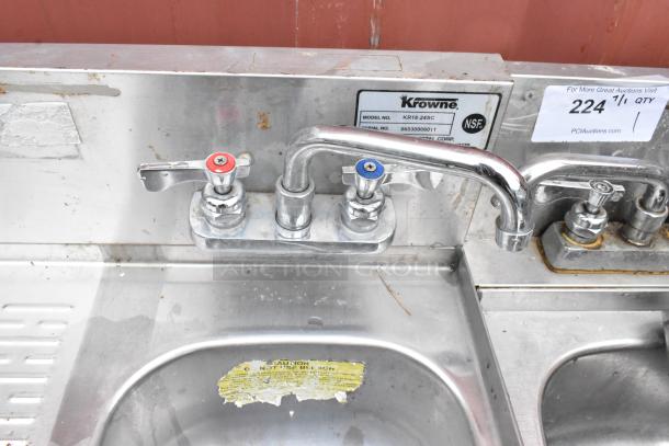 Krowne stainless steel commercial sink with dual faucets, model KR18-245C, NSF certified, visible wear and caution label.