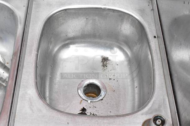 Stainless steel kitchen sink with visible wear and grime near the drain area; appears to need cleaning.
