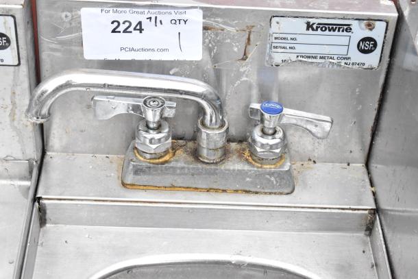 Krowne stainless steel commercial sink faucet with dual handles, NSF certified, visible wear and rust around base.