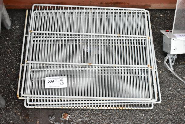 Stack of metal wire shelving, light rust spots, quantity label indicates 5 units. Suitable for storage or retail use.