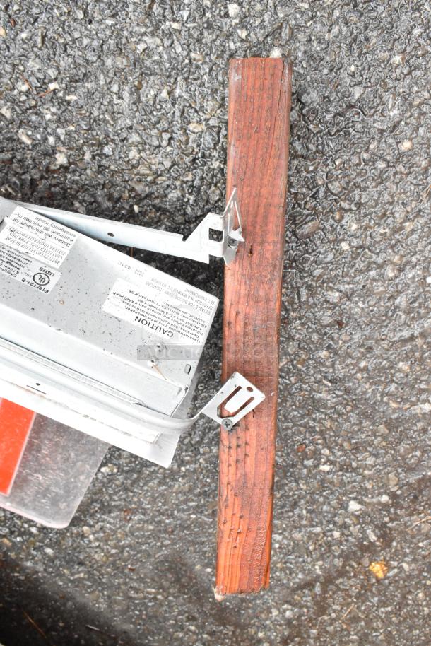 Metal electrical bracket attached to weathered wood plank. Labels detail UL certification and caution instructions. Good condition.