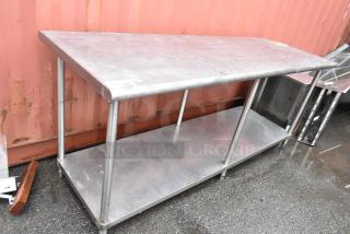 Stainless steel work table with lower shelf. Used condition, shows wear. Ideal for kitchen or industrial use.
