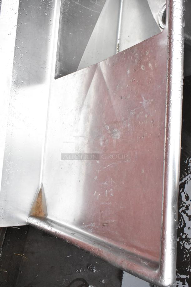 Stainless steel sink with visible wear and water marks, featuring a drain hole. Edges show minor rust and discoloration.