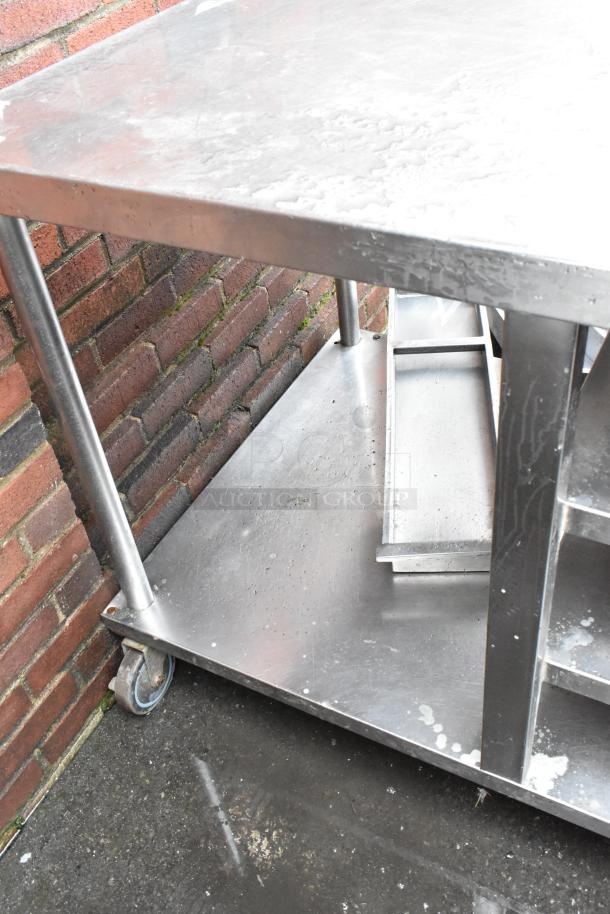 Stainless steel utility cart with wheels, durable construction, showing signs of wear, ideal for industrial use.