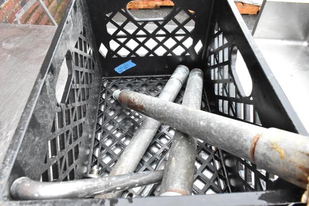 Black crate containing used metal pipes, showing signs of rust. Blue tape with "BX12" label inside. Auction item in used condition.