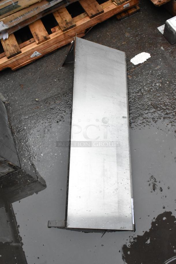 Rectangular metal shelf, stainless steel, lightly scratched, resting on a wet surface. No visible labels or markings.