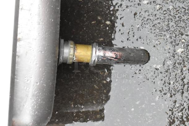 Close-up of a wet pipe connection with metal fittings. Visible corrosion and wear, indicating used condition.