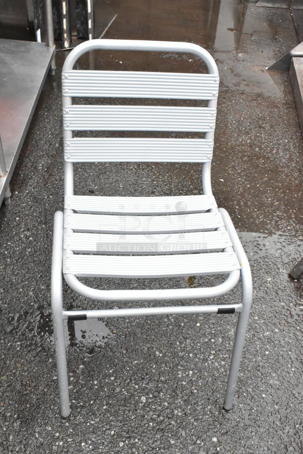 Silver metal outdoor chair with slatted design and visible screws. Good condition, suitable for patios or gardens.