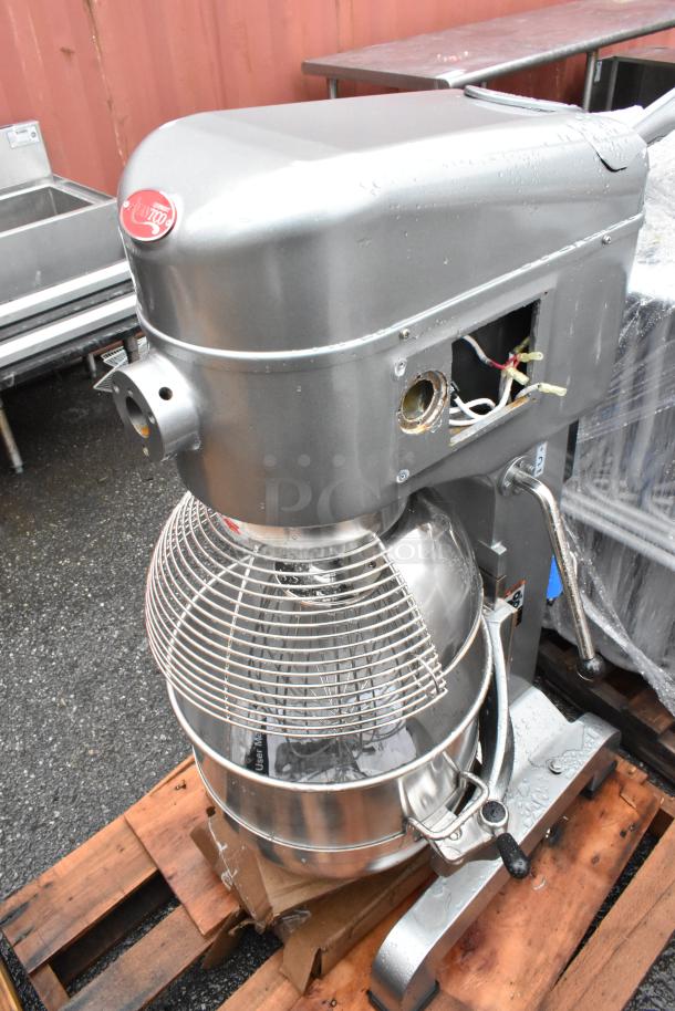 Industrial Planetary Mixer in gray, with a stainless steel bowl and wire guard. Missing a cover plate on the side. Used condition.