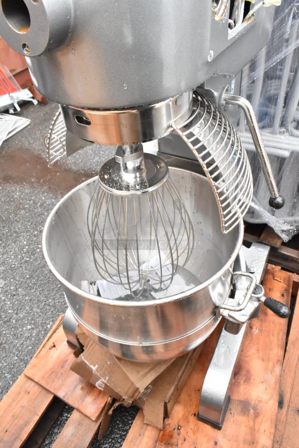 Commercial stand mixer with stainless steel bowl and wire whisk attachment, protective guard, and side lever, in good condition.