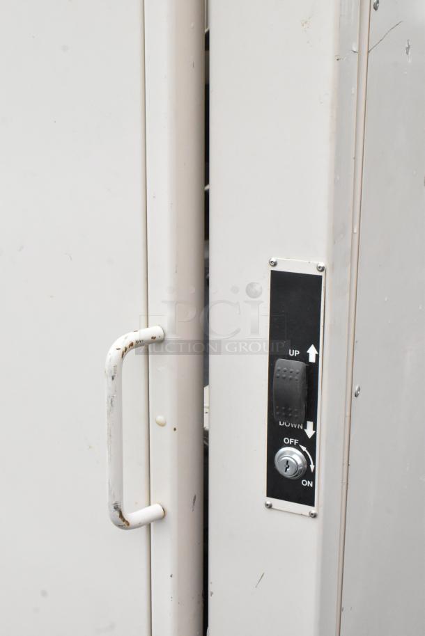 White industrial control panel with a metal handle and a switch labeled "UP," "DOWN," "OFF," "ON." Some surface wear visible.