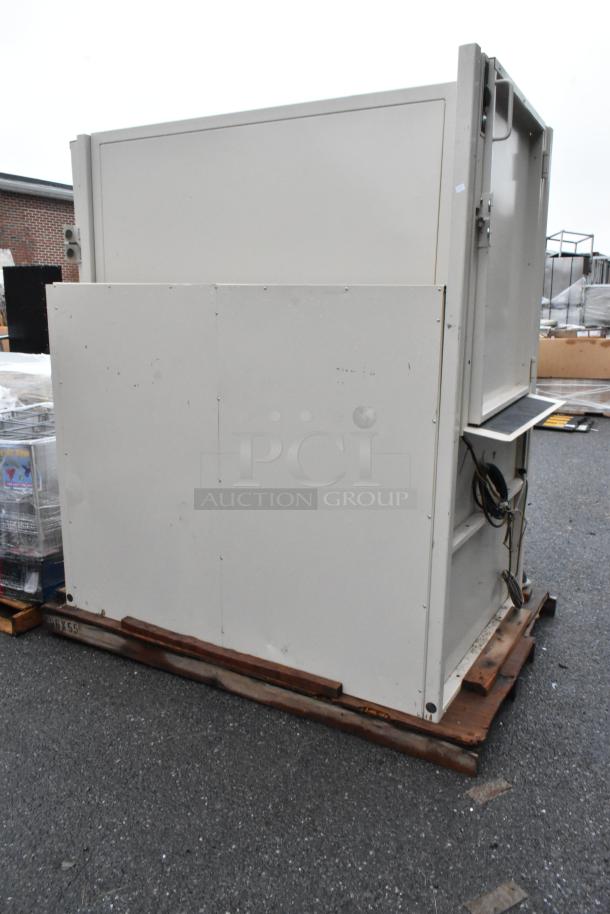 Large industrial equipment unit on pallet, metal construction, grey color, visible wiring; appears used with some scuff marks.
