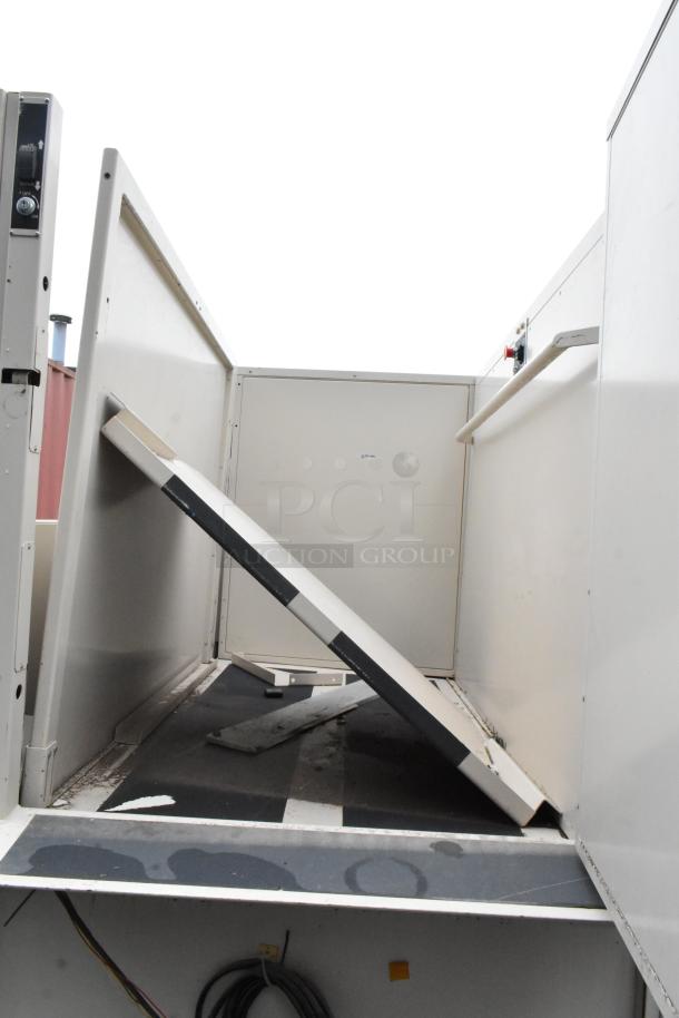 Industrial lift platform in used condition, featuring a slanted loading ramp and safety rails, with control panel visible.