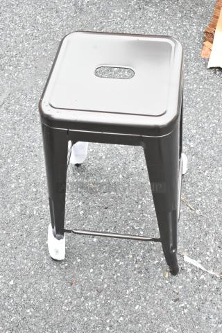 Metallic square stool with a hole in the seat for easy handling, in good condition, protective foot coverings visible.