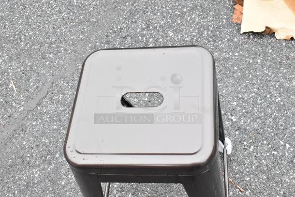 Metal folding stool with square seat and handle hole, in good condition. Features sturdy black finish suitable for indoor or outdoor use.