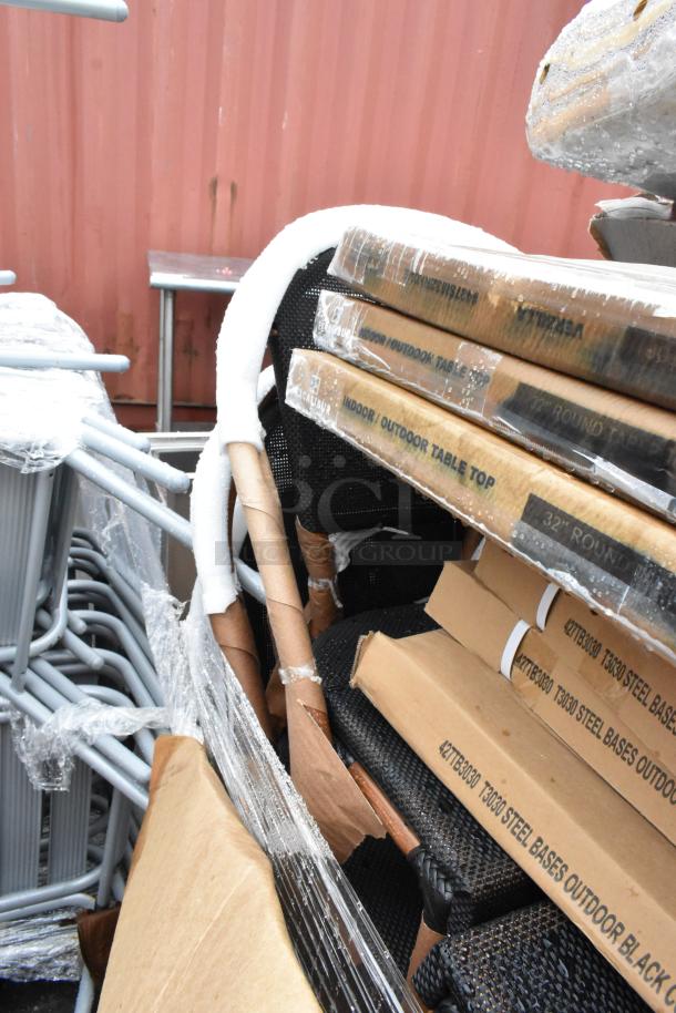 Stack of boxed indoor/outdoor table tops and steel bases with protective wrap. Labels indicate new condition.