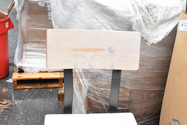 Wooden chair with metal supports, backrest showing wear mark, wrapped packaging and cardboard in the background.
