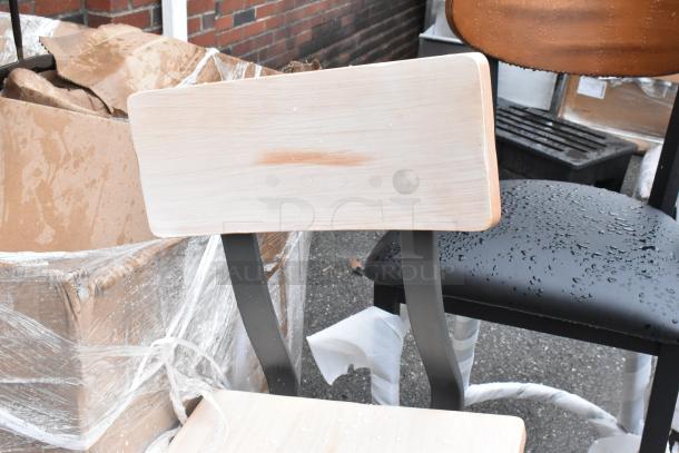 Wooden chair with metal legs, light finish, in used condition with water droplets. Background shows packaging and more chairs.