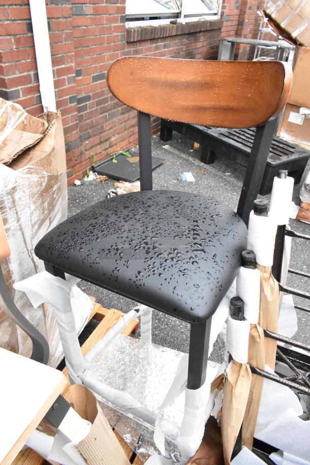 Wood-backed chair with black cushioned seat, water droplets visible. New condition, partially wrapped for protection.