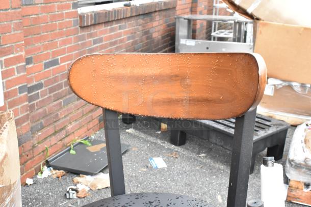 Wooden chair with water droplets on backrest, black metal frame, minor scratches, no visible tags. Good condition.