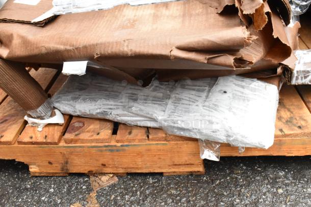 Damaged, partially unwrapped brown cardboard package on wooden pallet, showing exposed plastic-wrapped contents.
