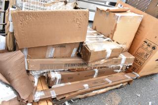 Stack of damaged cardboard boxes, some marked "ITEM#109AP," with visible tape and wear, indicating potential shipping or storage issues.