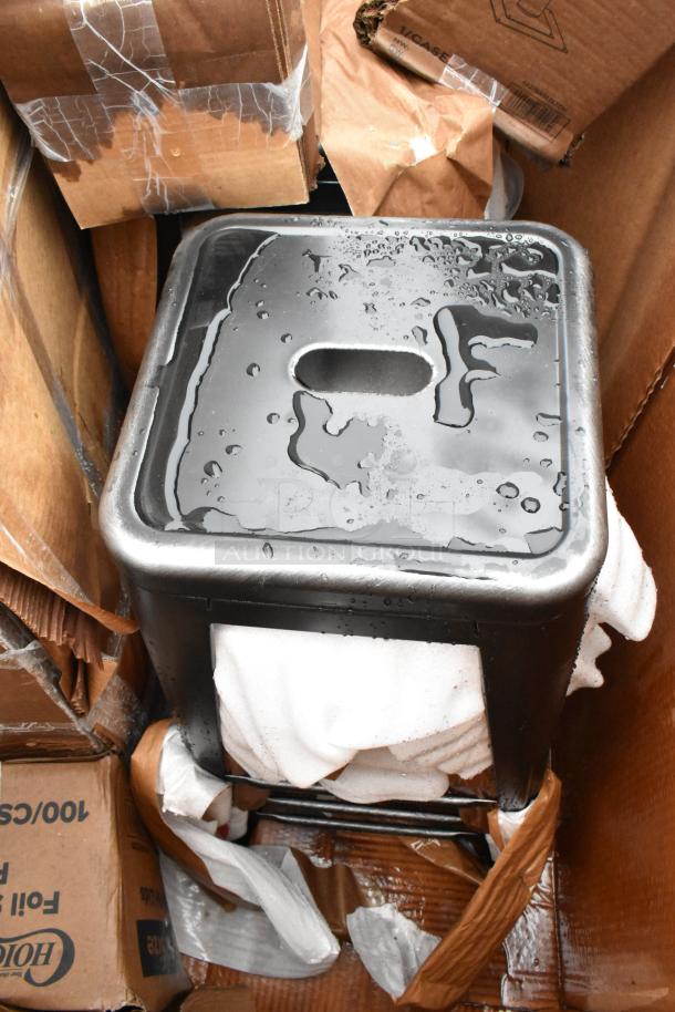 Metal stool with water droplets, square seat, and rectangular handle. Surrounded by cardboard boxes and packing materials.