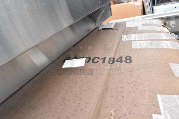 Close-up of a large metal cutting edge on a cardboard sheet with the marking "600DC1848." Visible wear on cardboard.