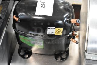 Secop SC15MNX compressor, black, R290 refrigerant, thermally protected; includes model and safety labels, good condition.