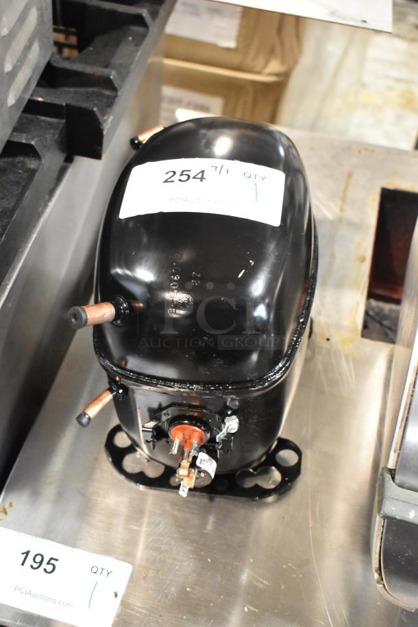 Black refrigeration compressor, lightly used, with copper pipe fittings. Auction tag "254," indicates quantity and auction site.